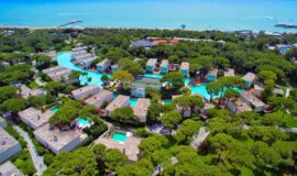 Aerial view of Rixos Premium Belek resort in Turkey, showcasing luxury villas surrounded by lush greenery and winding swimming pools near the beachfront.