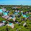 Aerial view of Rixos Premium Belek resort in Turkey, showcasing luxury villas surrounded by lush greenery and winding swimming pools near the beachfront.