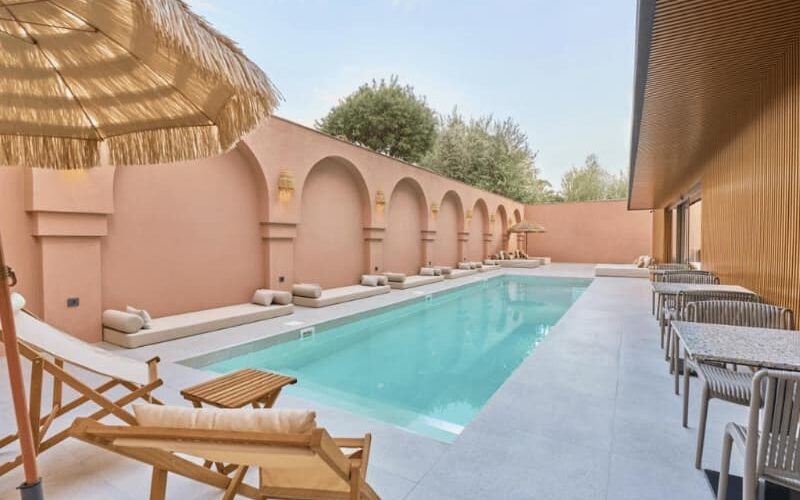 Relaxing pool area with sun loungers and tropical umbrellas at La Maja Hotel Antalya, featuring elegant arches and modern design